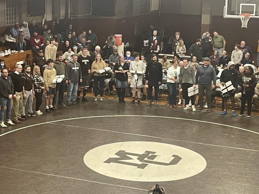 All+5+senior+wrestler+standing+with+their+families+being+honored+for+Senior+Night+before+the+meet.+