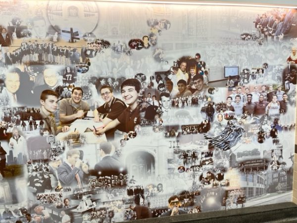 The mural on the wall of in first floor hallway features some current and past alumni staff.