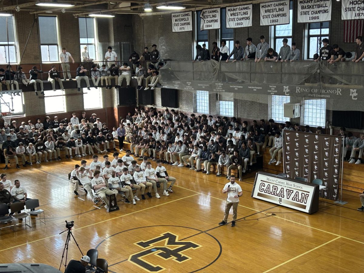 Head coach Alex Tsirtsis speaks to the school during the gathering February 29, 2024 in Alumni Gym to celebrate the wrestling teams state championship.