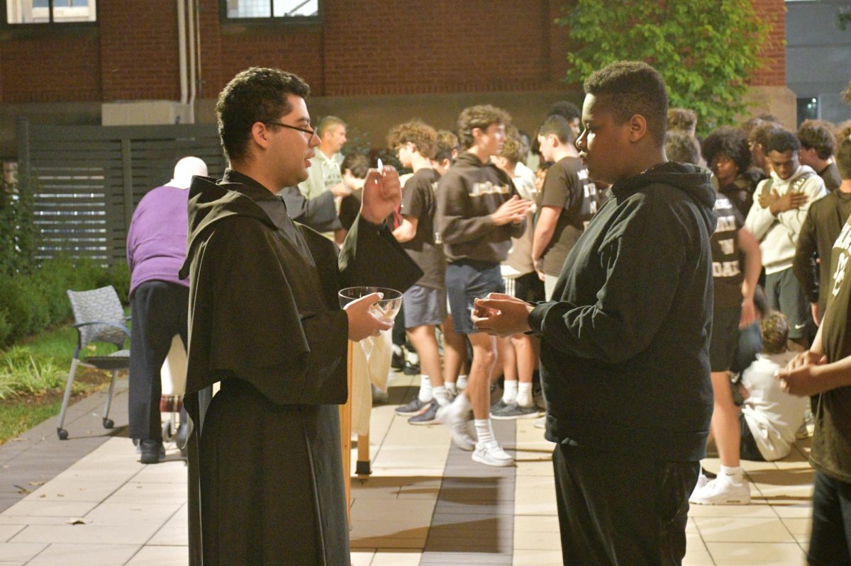 Brother Eduardo Vega helps administer the Eucharist to Students during Freshmen Late Night.