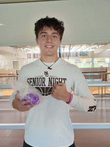 Senior and Student Council president Christos Dimas shows off the purple bracelets MC students received for donating to A New Direction on Friday, October 25, 2024. Purple is the color for domestic violence awareness.