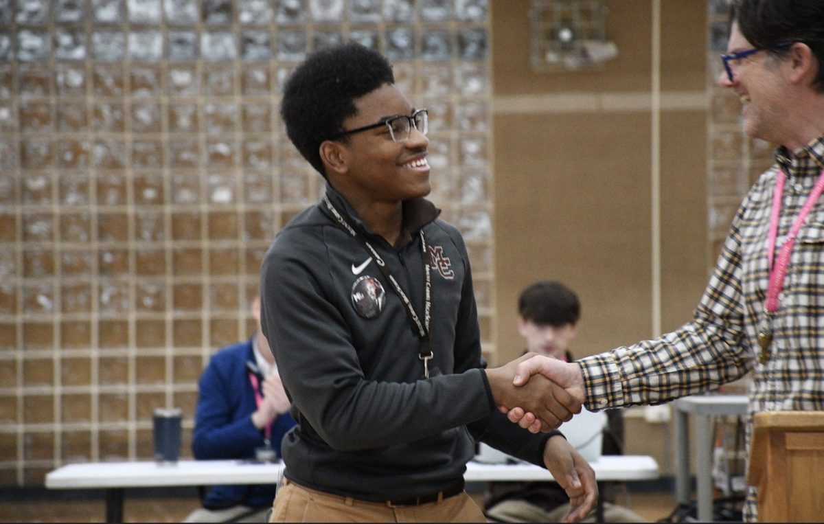 Mr. Matt Petrich (right) shakes hands with Aaron Hyler (left) after informing Hyler that he will receive the Henriette DeLille Award for Student Leadership at Holy Name Cathedral's annual African American Heritage Prayer Service on February 20.